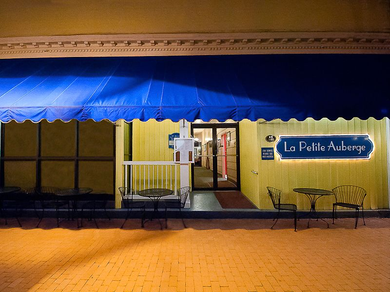 Image features the front of La Petite Auberge Restaurant in Fredericksburg, Virginia. The shot was taken at night and shows the blue awning and the French Style facade with light colors.   